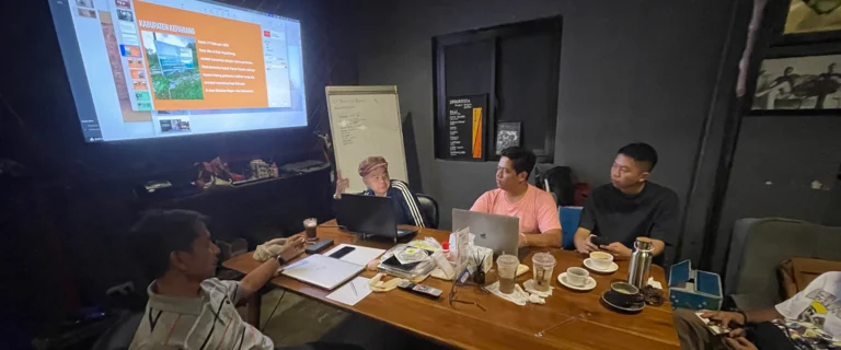 Team meeting around a table in a dim room with a projected presentation