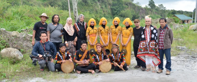 Film crew and local villagers in traditional yellow costumes posing outdoors in the highlands
