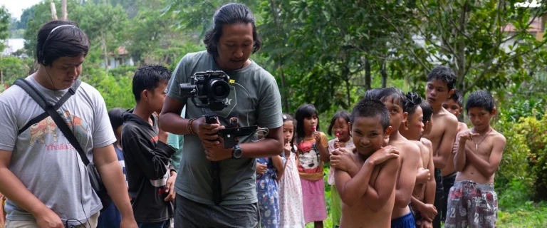 Cameraman filming among a group of curious village children